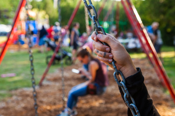 一个年轻女人的手在一个公园的秋千链的特写照片图片下载