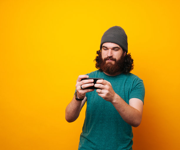 留着胡子的嬉皮士用黄色背景打电话图片下载