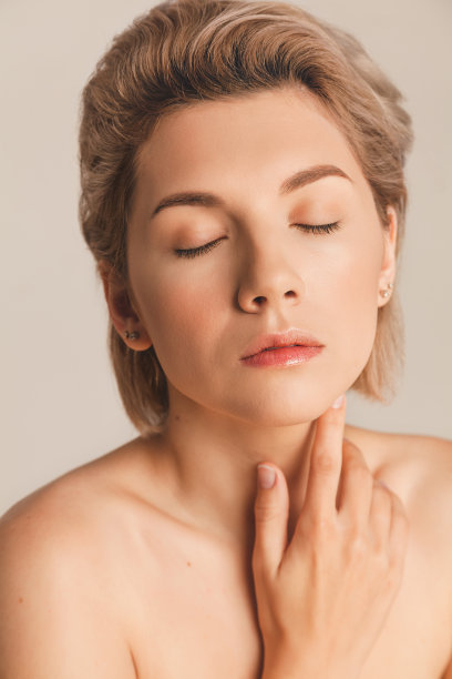 美丽的女孩闭上眼睛，摸了摸脖子。甲状腺治疗图片下载