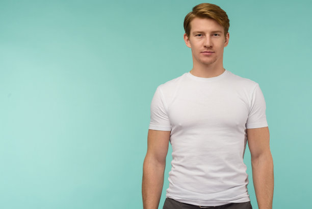 运动的年轻人站在白色的thirt在蓝色的背景图片下载