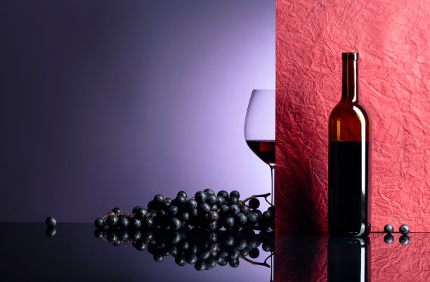 黑桌子上放着一瓶和一杯红酒。图片下载