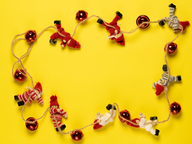 圣诞花环是用彩色的针织玩具编织而成的，在明亮的黄色背景上摆着红色的球。圣诞节和新年的概念。放置在地图上，俯视图图片下载