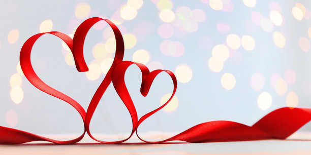 蓝色背景上的两颗红丝带心，配上金色的灯光。图片下载