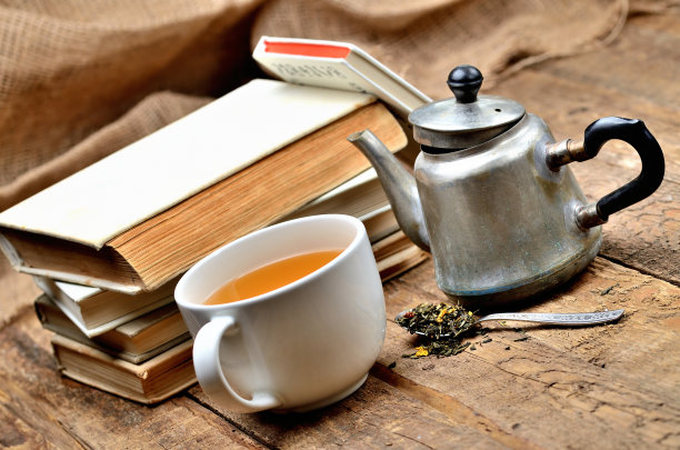 一堆古书，一杯红茶，一把老茶壶和一把匙散着茶叶图片下载