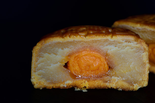 一个传统的中国月饼的特写，切开，在黑暗的背景与文字空间图片下载