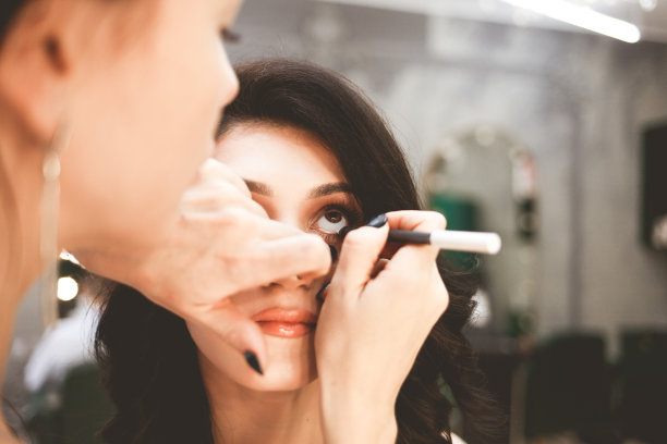 化妆师用眼线笔画眼睛。专业美容师为美女化妆图片下载