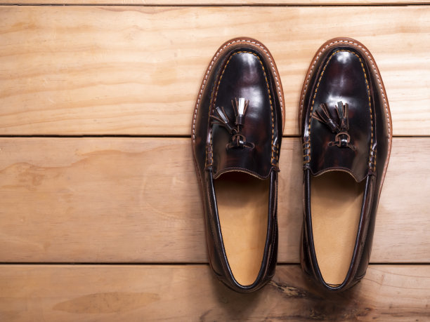 男子流苏乐福鞋与光滑的抛光皮革在一个木制的背景。时尚广告棕色鞋子照片。俯视图图片下载