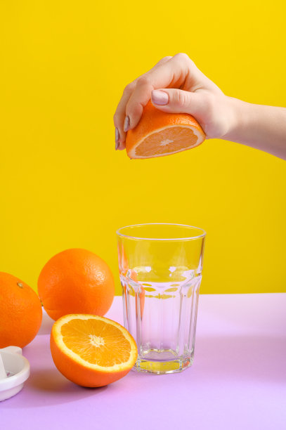 从橙子里挤出橙汁。明亮背景时尚照片图片下载
