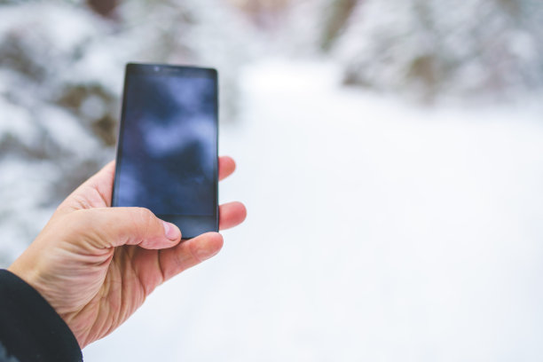 手机在手里。在冬天的森林里使用智能手机图片下载