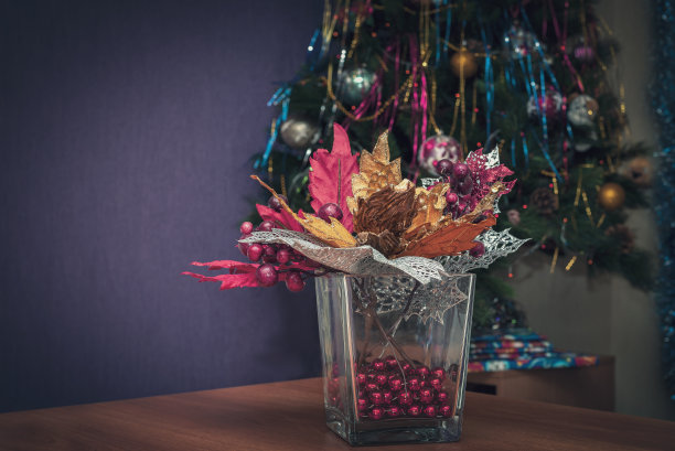 圣诞静物画，花瓶里有一束花，背景是圣诞树。图片下载