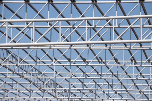 蓝天背景下的钢桁架。工业厂房屋顶金属钢结构。图片下载