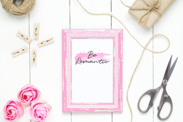 模拟相框的情人节概念。俯视图模拟的照片框架与工艺装饰和玫瑰花在白色的木材背景。图片下载