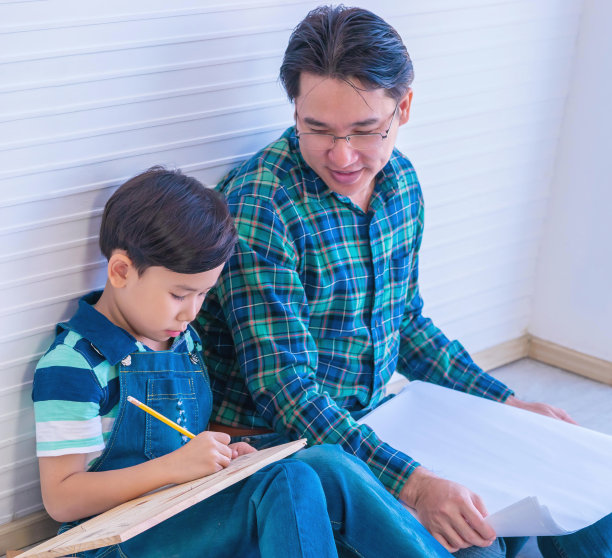 父亲正在教儿子自己动手做家装工作，以增进父母和家庭的感情。图片下载