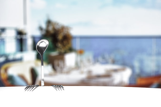 在阳光明媚的夏日，从勺子和叉子，坐在海滩酒吧的桌子上的人的形象。主题餐饮经营。图片下载