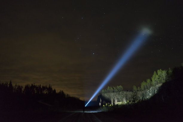 雨雾之夜，一个人站在户外，用手电筒照着图片下载