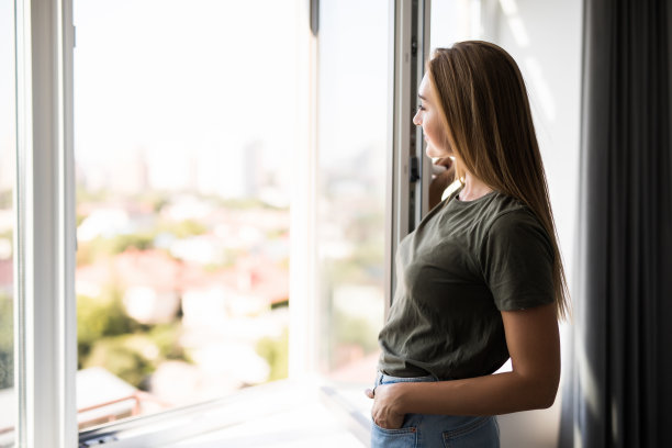 年轻女子在起居室打开窗户图片下载