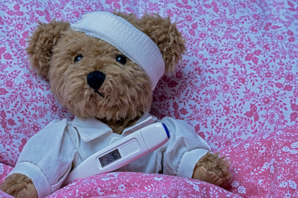 头部受伤的泰迪熊和发烧温度计图片下载