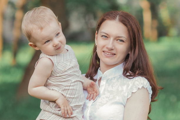 年轻的妈妈和她可爱的小女儿站在公园的草地上图片下载