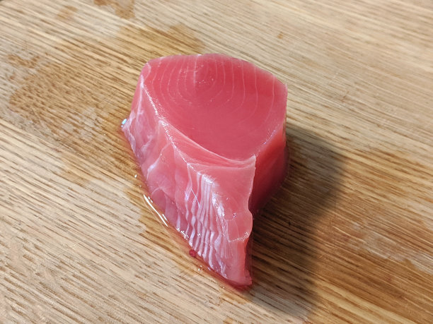 在切菜板上放着未包装的粉色金枪鱼片图片下载