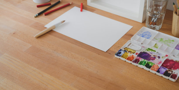 拍摄舒适的艺术家工作场所与素描纸和绘画工具在木桌上图片下载