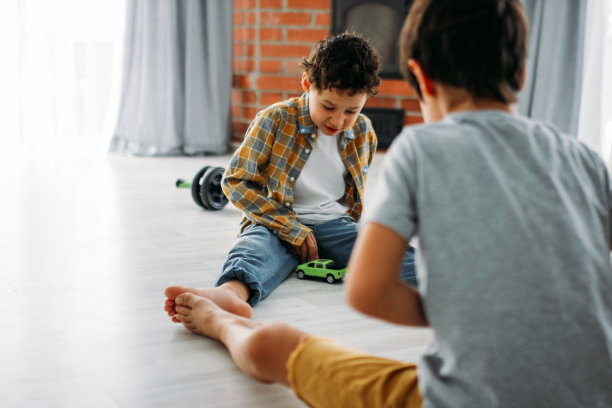两个兄弟之间的男孩真正的兄弟在休闲服装玩玩具车在家里图片下载