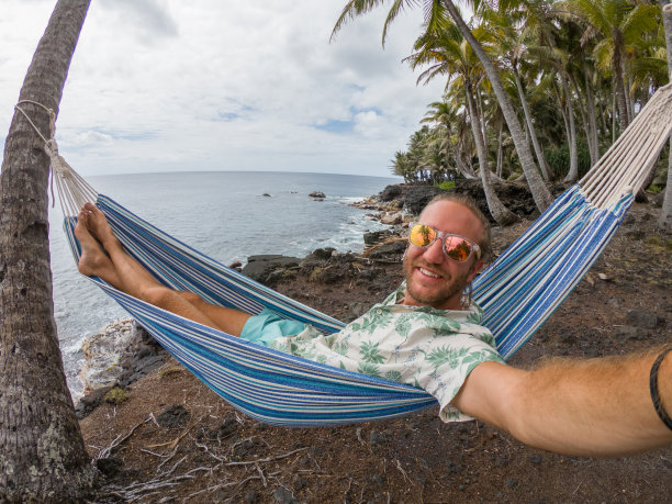 一个年轻人在吊床上自拍，去海滩度假图片下载