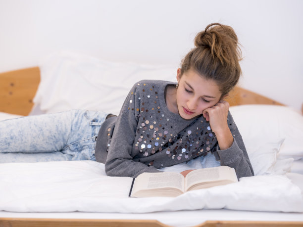 女孩躺在床上看书图片下载