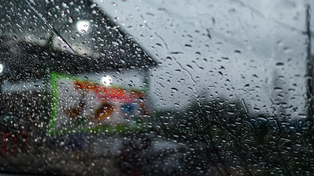 交通中的汽车和灯光模糊不清。雨点落在挡风玻璃上图片下载