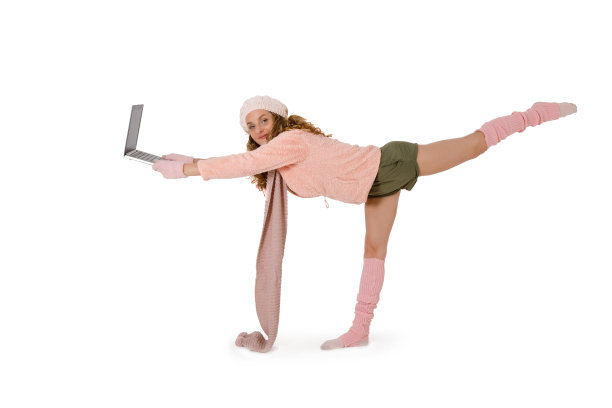 年轻漂亮的女人单腿站在笔记本电脑前工作图片下载