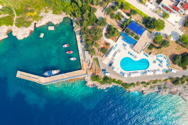 鸟瞰图的海岸清澈的蓝色的水，船，码头，酒店游泳池和绿树在夏季阳光明媚的一天在克罗地亚。俯瞰岩石海滩，游艇，建筑和森林。旅行图片下载