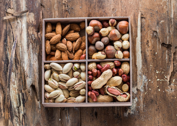 在木盒中混合坚果。点心混合干杏仁，榛子，花生和开心果。混合。可食用的，生的，有机的和素食。孤立的微距食物照片特写从上面的白色背景图片下载