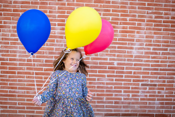 美丽的小女孩在一个有风的日子玩气球图片下载
