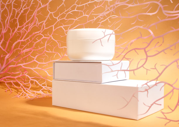 白色的奶油瓶立在沙棕色的背景上，珊瑚的枝杈和它们的影子。海滩上的皮肤护理。图片下载