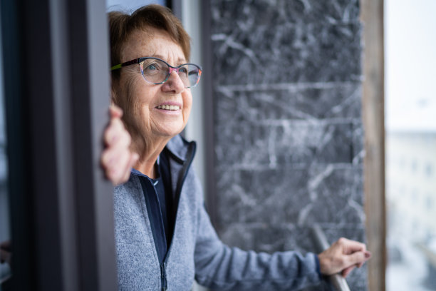 描绘冬日阳台上快乐微笑的老妇人图片下载