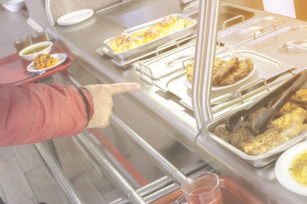 在一个公共餐厅里，盘子和食物放在一个托盘上，前面和背景用散景效果模糊图片下载