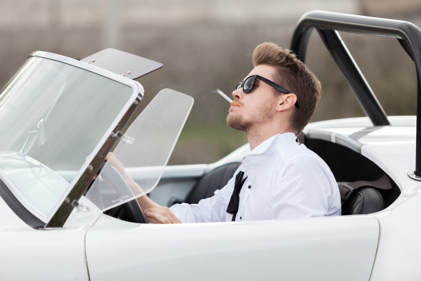 英俊的男人在一辆老爷车旁抽烟图片下载