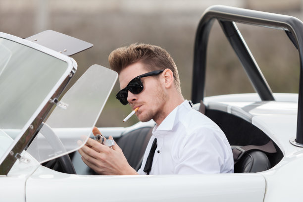 英俊的男人在一辆老爷车旁抽烟图片下载