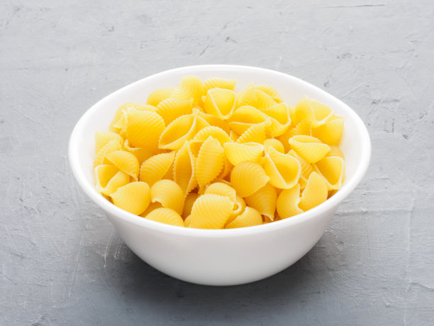 白色的意大利面杯，灰色的混凝土和米色的织物背景。健康饮食的概念图片下载