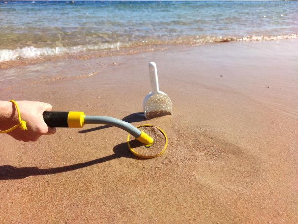 水下金属探测器和沙滩上的铲子照片：寻宝和旅游探险背景图片下载