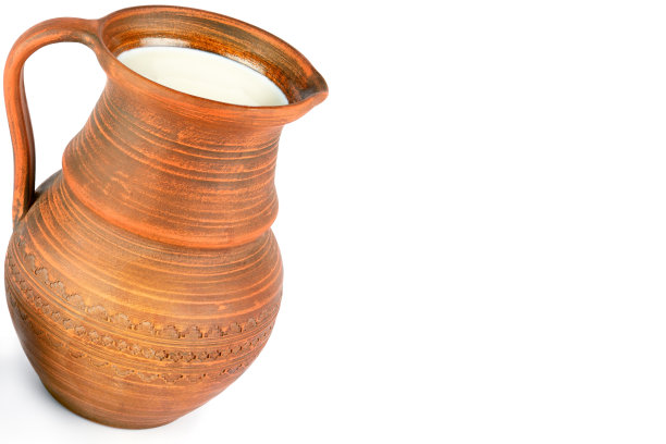 白色背景上有鲜奶的陶罐。图片下载