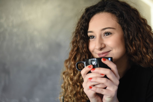 年轻女子手持咖啡杯或茶杯图片下载