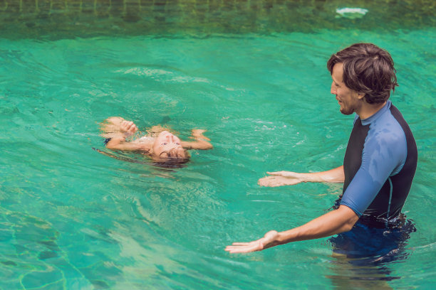 游泳男教练教孩子们在游泳池里快乐的游泳素材图片