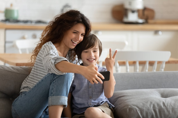 快乐的妈妈拿着智能手机和儿子自拍图片下载