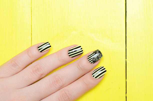 明亮的黄色指甲与黑色条纹和向日葵图案在黄色的背景图片下载
