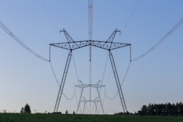 夏天的晚上，巨大的输电塔矗立在田野上图片下载