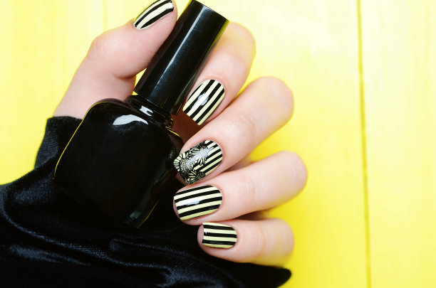 明亮的黄色指甲与黑色条纹和向日葵图案在黄色的背景图片下载