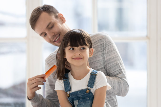 快乐的千禧单身父亲为女儿梳头发。图片下载