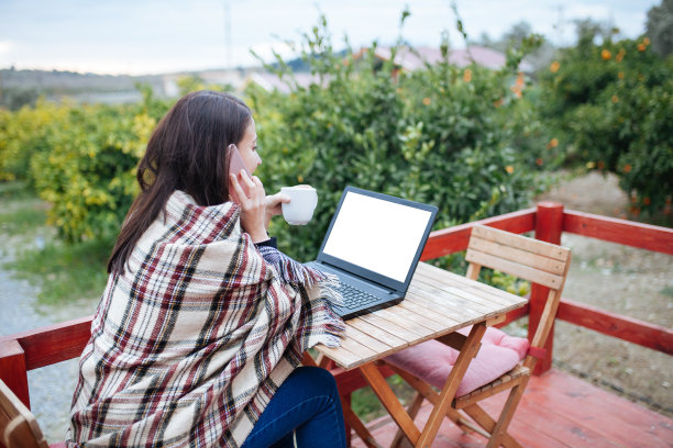 自由职业者女孩，拿着咖啡和笔记本在花园的门廊上。库存图片图片下载