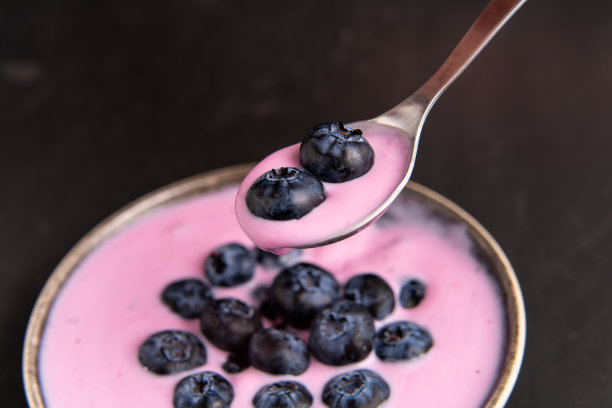 美味新鲜的蓝莓酸奶奶昔甜点在陶瓷碗站在黑色的桌子背景。图片下载