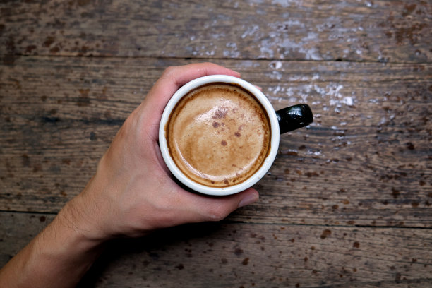 热咖啡杯放在木桌上，以花园为自然背景，清晨雨天的种植园背景——意象图片下载